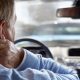 Man behind the wheel of his car, grasping his neck in pain