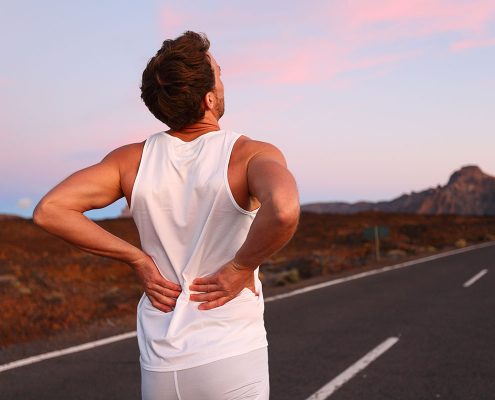 Runner grabbing his lower back with both hands, as if in pain