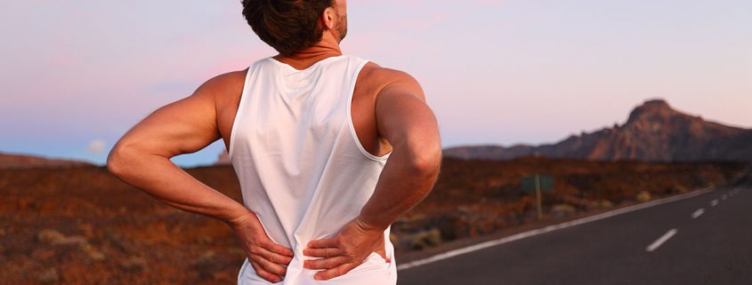 Runner grabbing his lower back with both hands, as if in pain