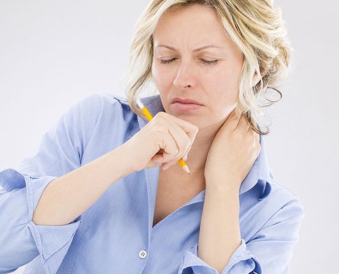 Woman scowling in pain and rubbing her neck