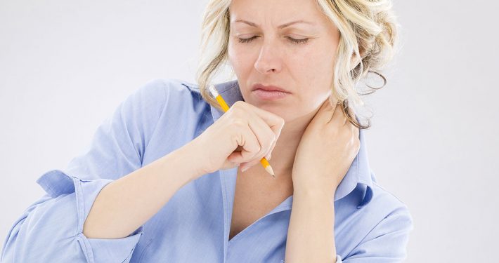 Woman scowling in pain and rubbing her neck