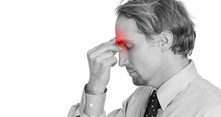 Man pinching the area between his eyes, as if his sinuses hurt