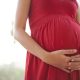 Close-up of a woman's hands clasped below her pregnant belly