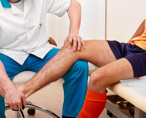 Close-up of a doctor or therapist assessing the leg of an athlete