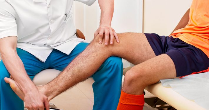 Close-up of a doctor or therapist assessing the leg of an athlete