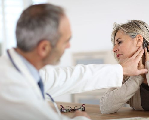 A woman showing her doctor where her neck pain is located