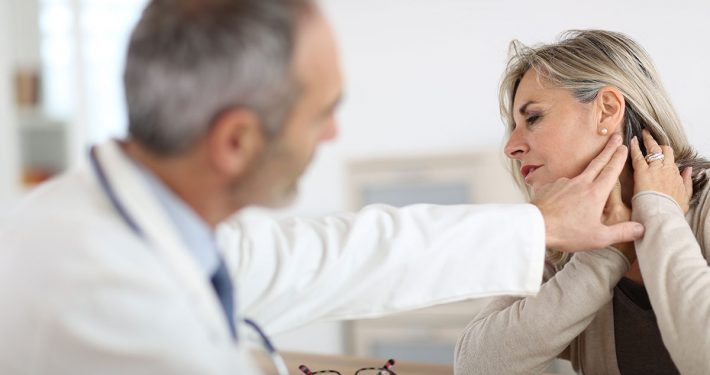 A woman showing her doctor where her neck pain is located