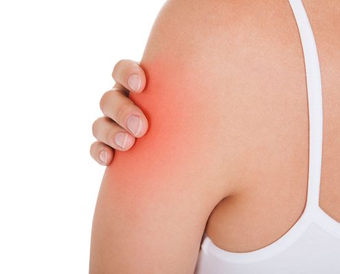 Close-up of a woman grasping her upper arm, a spot of pain highlighted in red