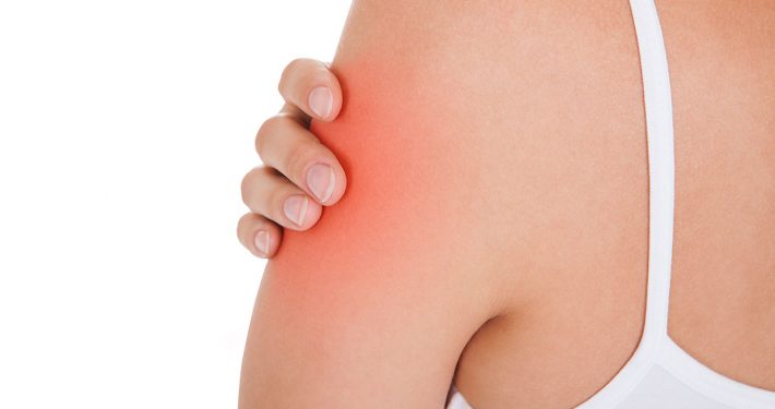 Close-up of a woman grasping her upper arm, a spot of pain highlighted in red