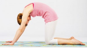 Woman performing cat pose, on hands and knees, back arched and head down