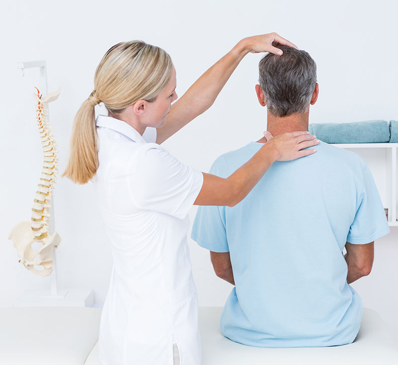 A female chiropractor assesses the spinal alignment of a male patient