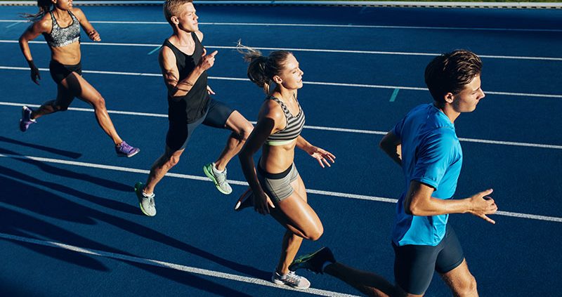 A co-ed and multi-racial group of young athletes running on a track