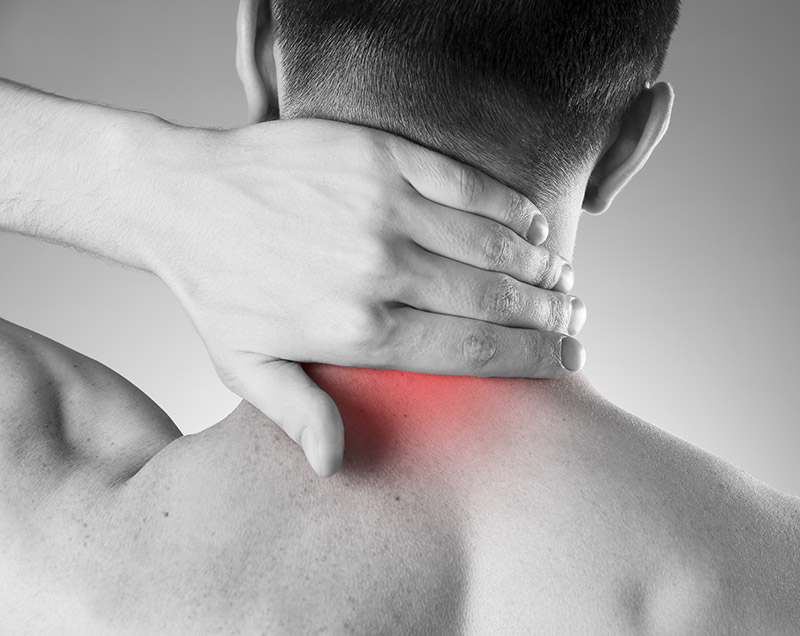 Close-up of a man with his hand on the back of his neck, a red area added to indicate pain