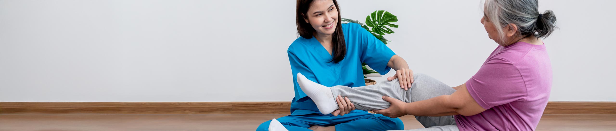 Physical therapist Asian woman, doing leg physiotherapy for elderly woman, to treat osteoarthritis and nerve pain in the leg